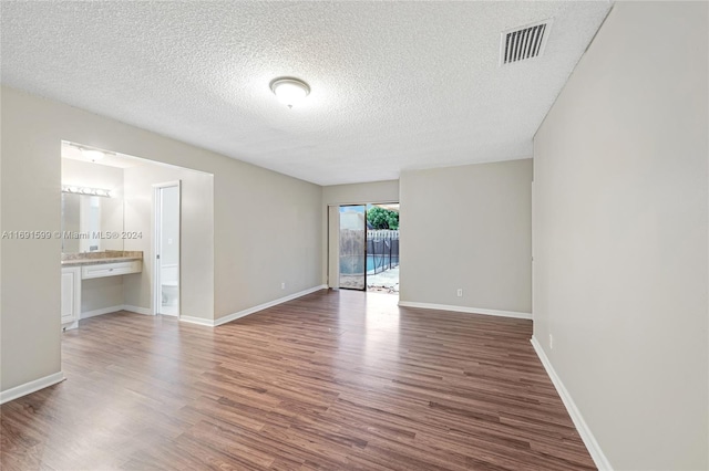 unfurnished room with a textured ceiling and dark hardwood / wood-style flooring