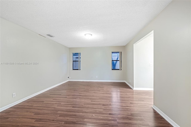 empty room featuring dark hardwood / wood-style flooring and a textured ceiling