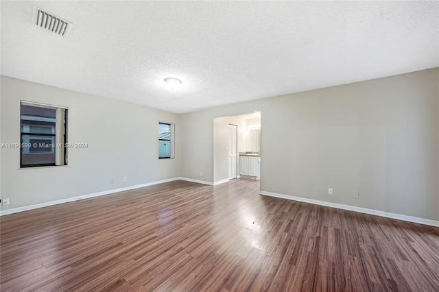 spare room featuring a textured ceiling and dark hardwood / wood-style floors