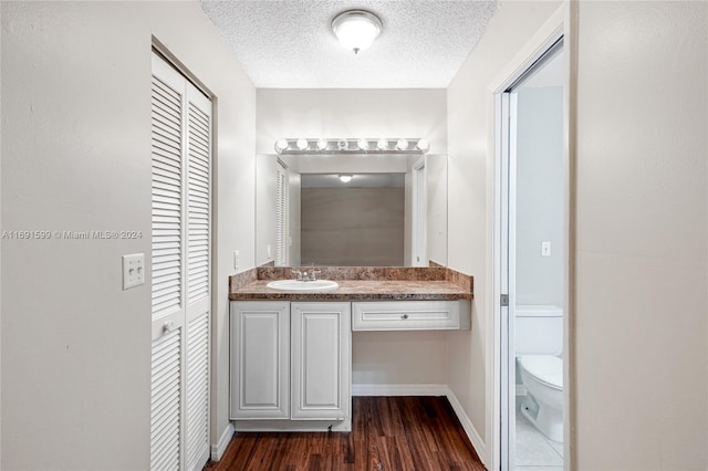 bathroom with hardwood / wood-style floors, vanity, a textured ceiling, and toilet