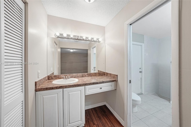 bathroom with toilet, vanity, a textured ceiling, and hardwood / wood-style flooring