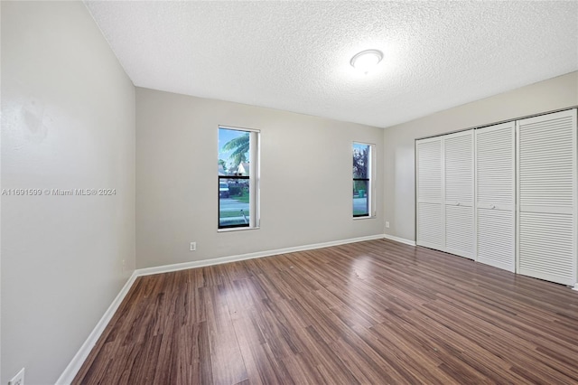 unfurnished bedroom featuring dark hardwood / wood-style flooring, a textured ceiling, and a closet