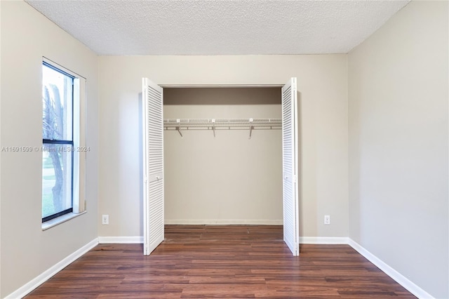 unfurnished bedroom with a textured ceiling, dark hardwood / wood-style flooring, and a closet