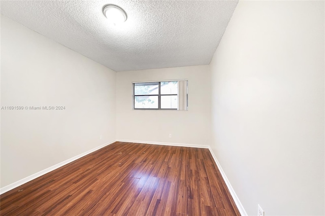 unfurnished room with a textured ceiling and dark wood-type flooring