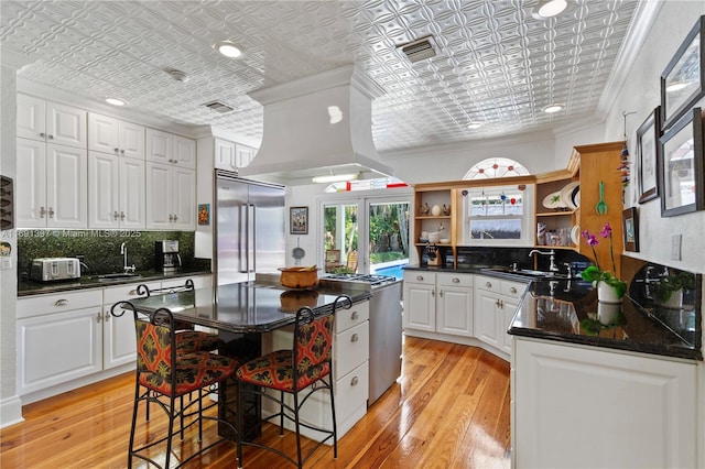 kitchen featuring crown molding, appliances with stainless steel finishes, an ornate ceiling, and open shelves