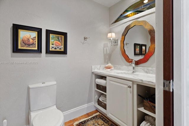 half bathroom featuring vanity, baseboards, toilet, and wood finished floors