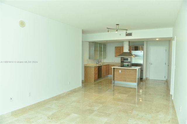 kitchen featuring appliances with stainless steel finishes, sink, wall chimney exhaust hood, and a center island