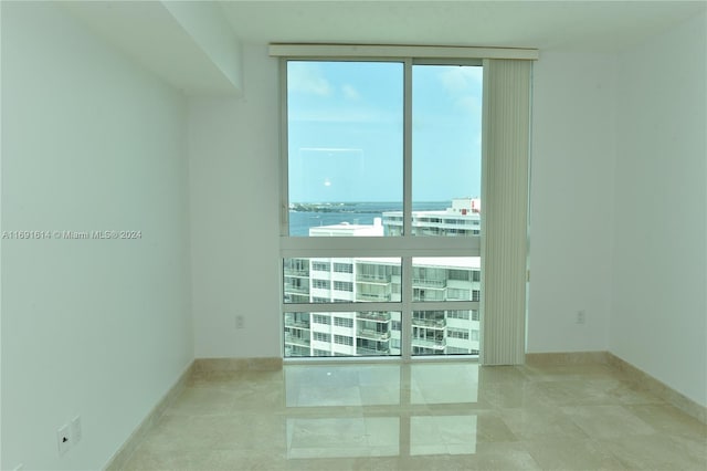 spare room with a water view and floor to ceiling windows