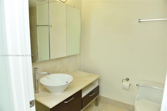 bathroom with toilet, vanity, and tile patterned flooring