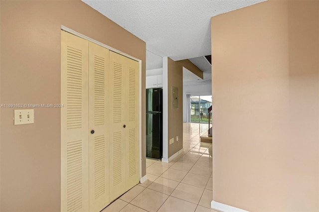 hall featuring a textured ceiling and light tile patterned flooring