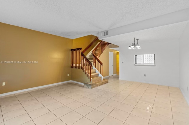 spare room featuring light tile patterned flooring, a textured ceiling, and an inviting chandelier