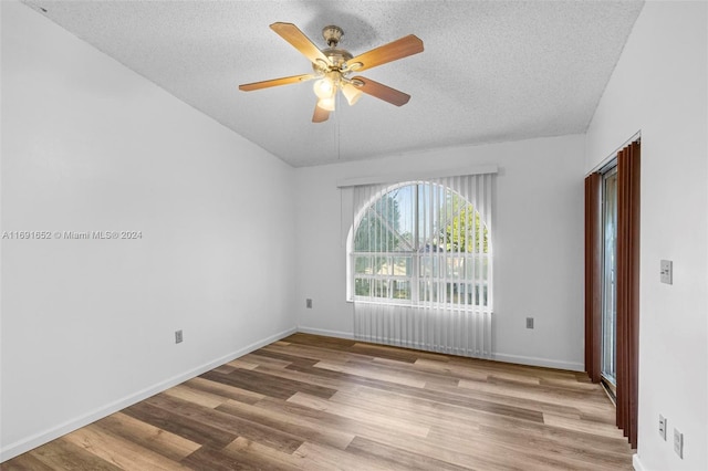 unfurnished room with ceiling fan, vaulted ceiling, a textured ceiling, and light hardwood / wood-style flooring