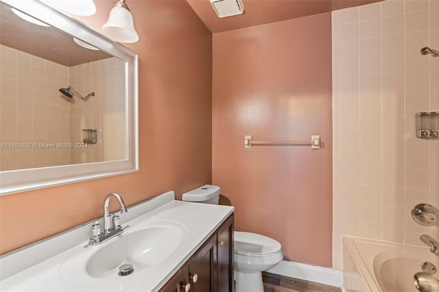 full bathroom featuring hardwood / wood-style flooring, vanity, toilet, and tiled shower / bath