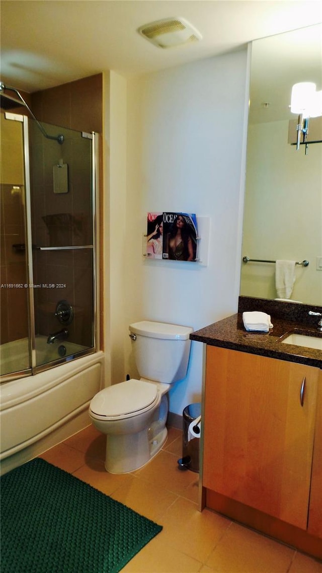 full bathroom with shower / bath combination with glass door, tile patterned flooring, vanity, and toilet