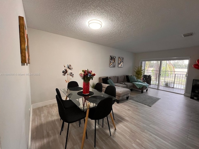 dining area with wood-type flooring and a textured ceiling