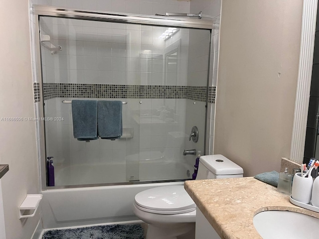 full bathroom with vanity, combined bath / shower with glass door, and toilet