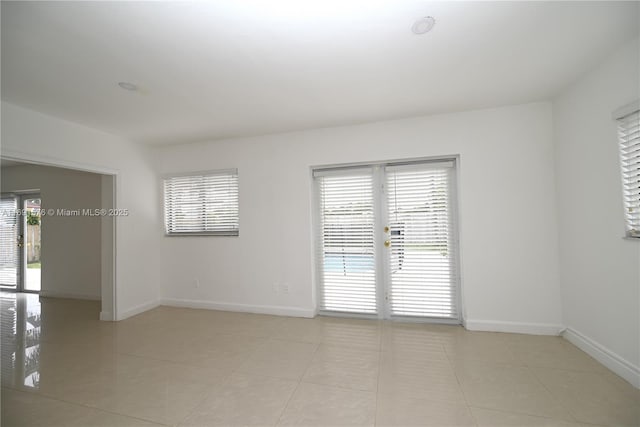 tiled spare room featuring french doors