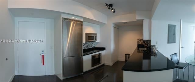 kitchen with white cabinetry, electric panel, appliances with stainless steel finishes, and tasteful backsplash