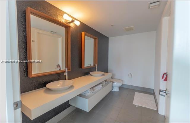 bathroom featuring toilet, vanity, and tile patterned flooring