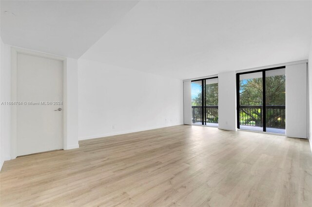 spare room featuring expansive windows and light hardwood / wood-style flooring