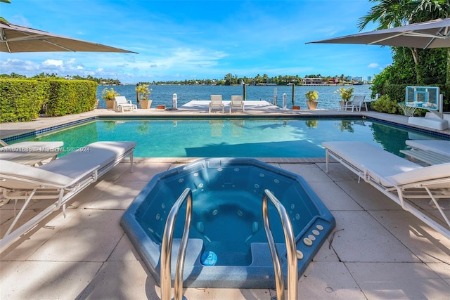 view of pool featuring an in ground hot tub, a water view, and a patio area