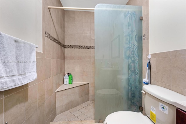 bathroom featuring toilet, tile walls, and a tile shower