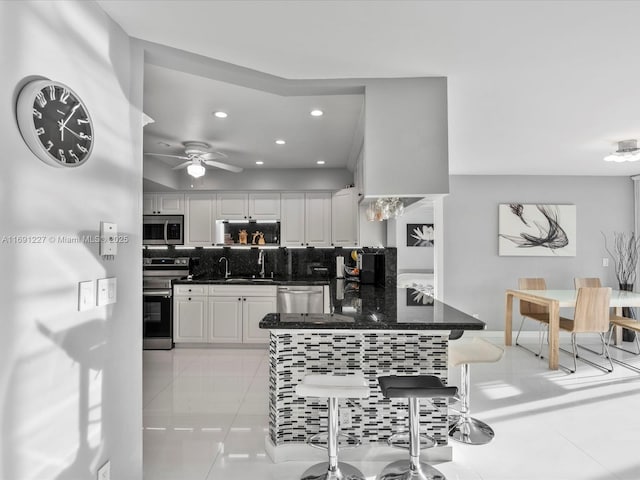 kitchen with white cabinetry, light tile patterned floors, kitchen peninsula, backsplash, and stainless steel appliances