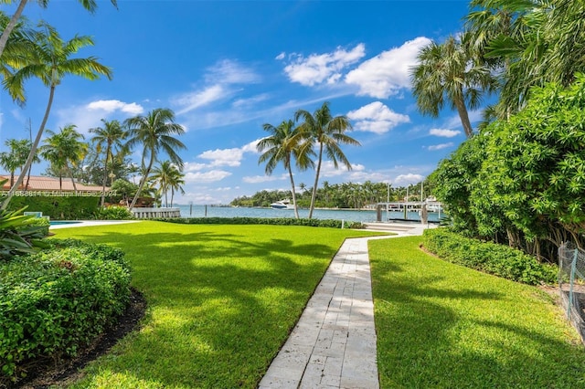 view of home's community featuring a dock, a water view, and a yard