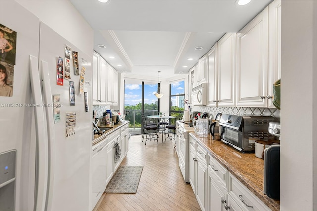 kitchen with light stone countertops, appliances with stainless steel finishes, light wood-type flooring, backsplash, and white cabinets