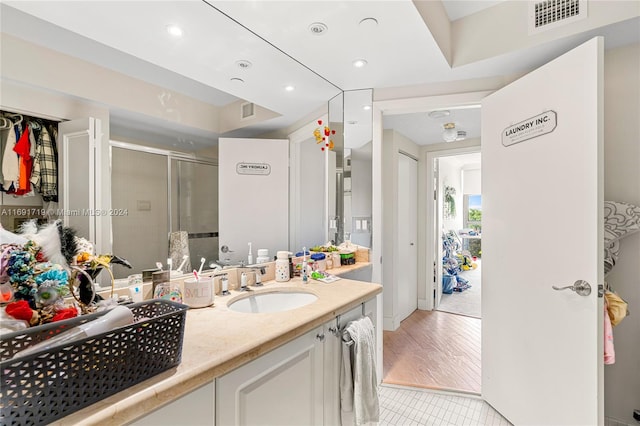 bathroom featuring vanity, wood-type flooring, and a shower with shower door