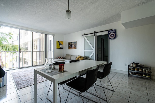 dining room with expansive windows, a barn door, a textured ceiling, and tile patterned flooring