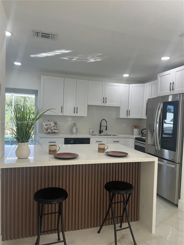 kitchen featuring a kitchen bar, white cabinetry, sink, and appliances with stainless steel finishes