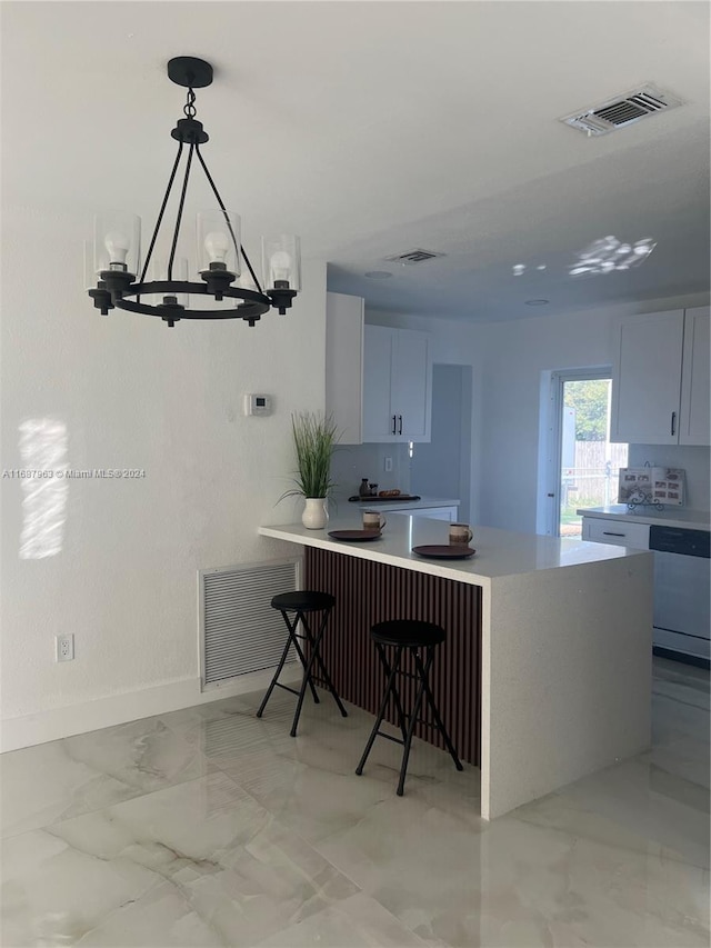 kitchen with an inviting chandelier, dishwashing machine, white cabinetry, and pendant lighting