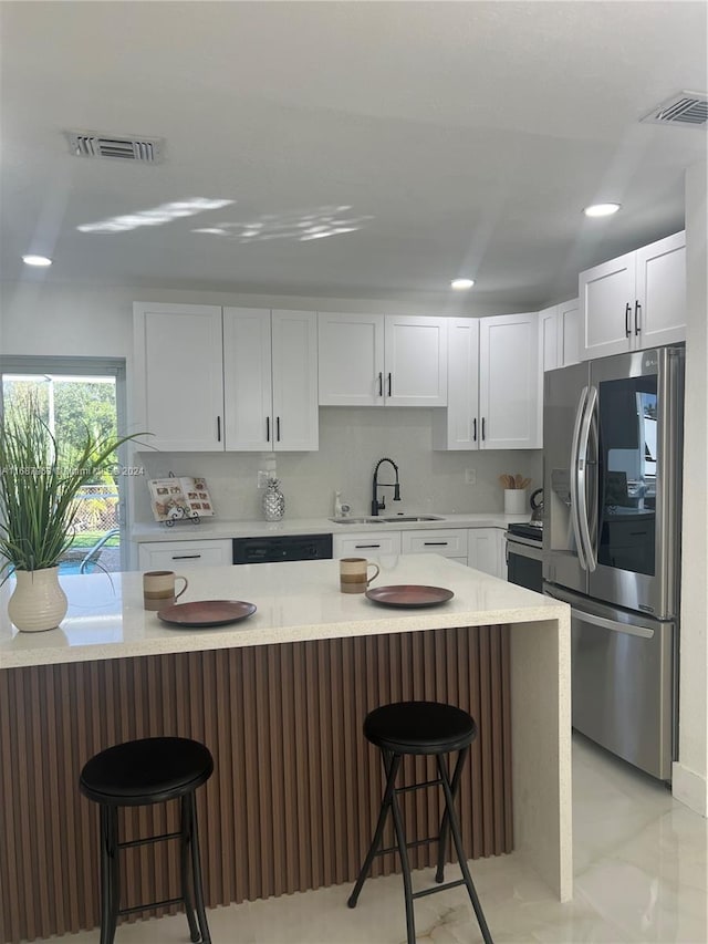 kitchen featuring white cabinetry, appliances with stainless steel finishes, sink, and a breakfast bar area