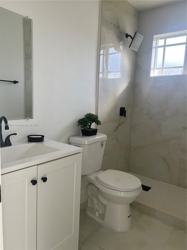 bathroom with tiled shower, vanity, and toilet