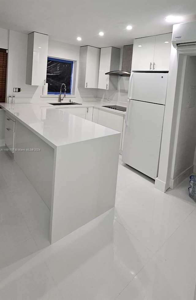 kitchen with black electric cooktop, white refrigerator, kitchen peninsula, wall chimney range hood, and white cabinetry