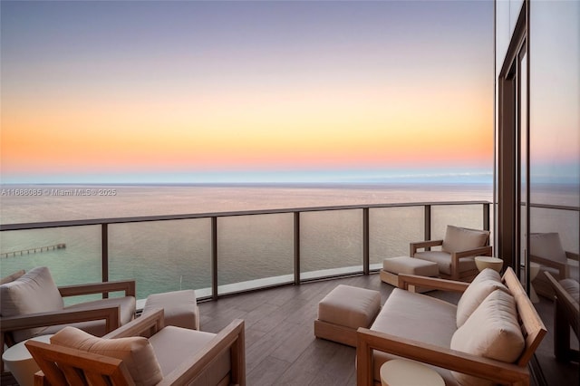 balcony at dusk featuring a water view