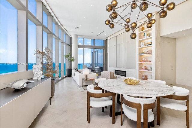 dining area featuring light parquet floors, a high ceiling, a notable chandelier, and a wall of windows