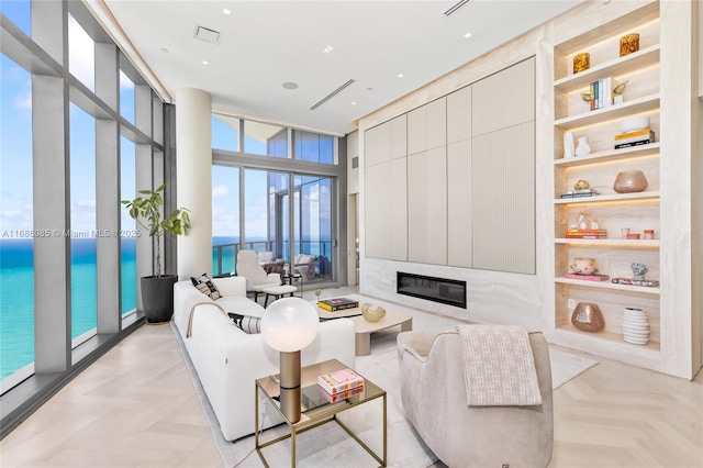 living room featuring floor to ceiling windows, a water view, and light parquet flooring