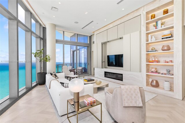 living room featuring floor to ceiling windows, a high end fireplace, built in features, and light parquet flooring