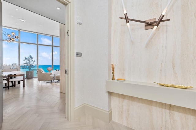 interior space featuring parquet flooring, a water view, and a wall of windows