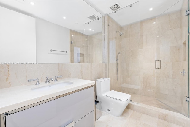 bathroom with a shower with door, vanity, tile walls, and toilet