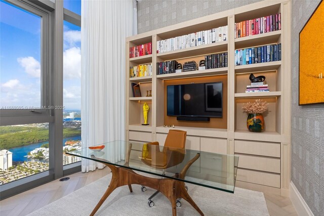 home office featuring a water view, built in features, and light parquet floors