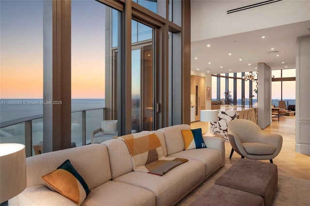 living room featuring a wealth of natural light, a water view, light parquet floors, and a wall of windows