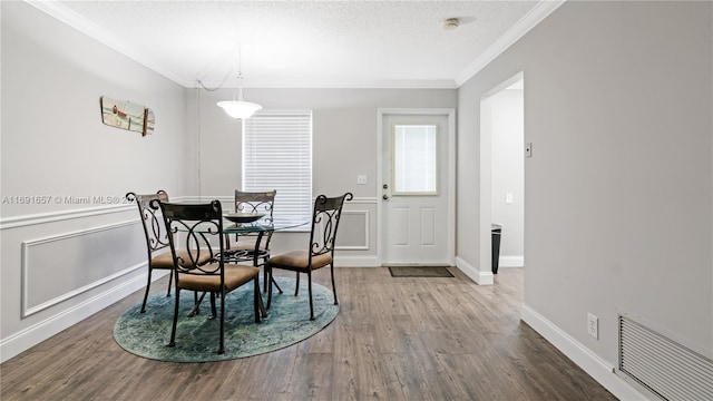 dining area featuring wood-type flooring, a textured ceiling, and crown molding