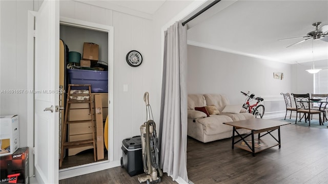 living room featuring dark wood-type flooring, ceiling fan, and crown molding