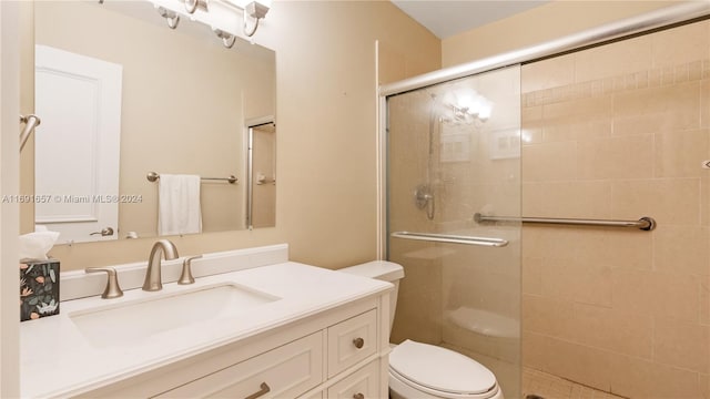 bathroom with vanity, toilet, and a shower with door