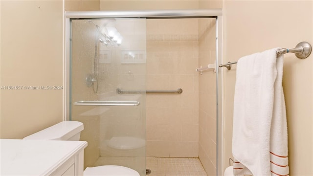 bathroom with an enclosed shower, vanity, and toilet