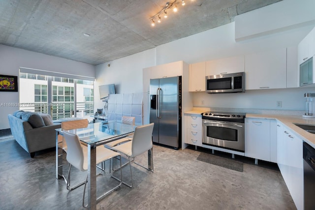 kitchen with concrete flooring, appliances with stainless steel finishes, and white cabinetry