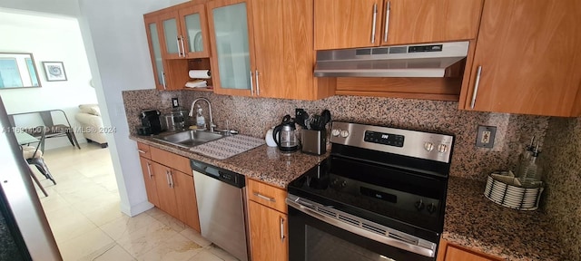 kitchen with appliances with stainless steel finishes, tasteful backsplash, dark stone countertops, and sink